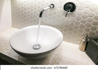 Modern hygienic wash basin with running clean water from tap faucet