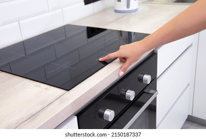 Modern induction hob in the kitchen. A woman's hand sets the heating power of the burner
