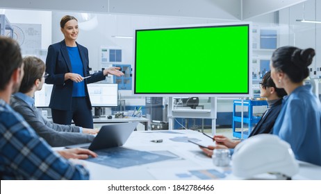 Modern Industrial Factory Meeting: Confident Female Engineer Uses Interactive Green Mock-up Screen Whiteboard, Makes Report to a Group of Engineers, Managers - Powered by Shutterstock