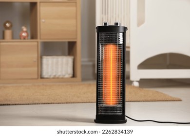 Modern infrared heater on floor in cozy room. Space for text