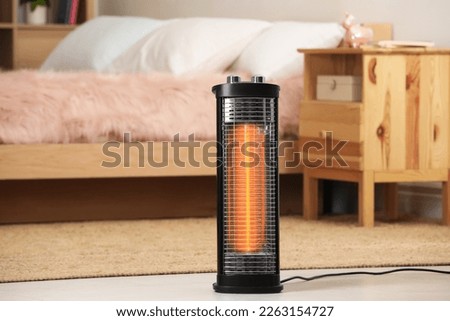 Modern infrared heater on floor in cozy room