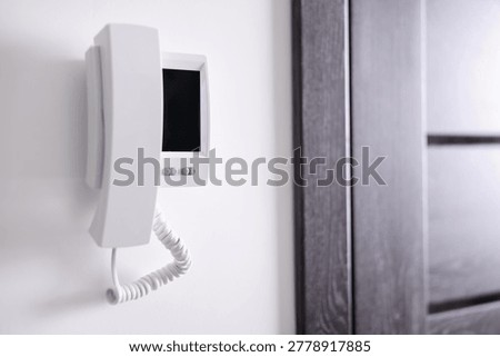 Modern intercom system with handset on white wall indoors, closeup