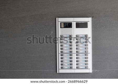Modern intercom system with multiple buttons and camera mounted on a gray exterior wall
