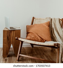 Modern interior design concept. Stylish rattan wooden chair, knitted plaid, ginger pillow. Cozy comfortable home office workspace with laptop. - Powered by Shutterstock