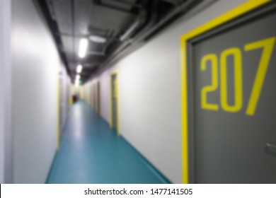 Modern interior design of long corridor in hostel. Empty hotel hall with doors. University dormitory. Cheap living in Travel. College. LED lightening. Energy Saving Technologies.