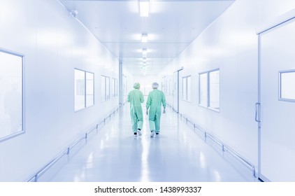 modern interior of laboratory or factory with back view of two scientist in coverall uniform, science development concept background