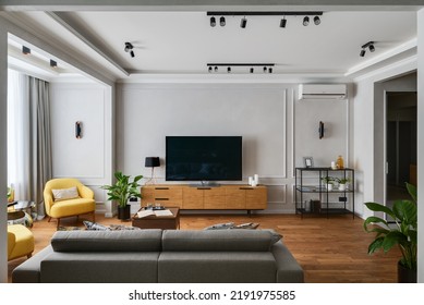 Modern Interior Of A Living Room In An Apartment With Yellow Armchairs And A TV Area, Direct Angle To The TV Stand And TV