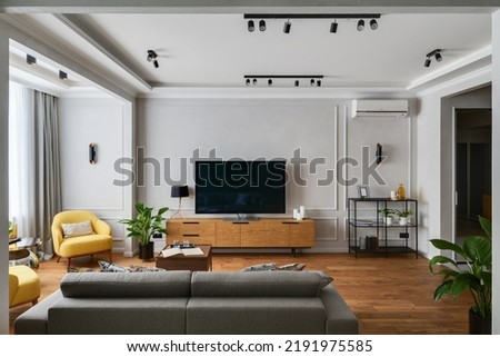 modern interior of a living room in an apartment with yellow armchairs and a TV area, direct angle to the TV stand and TV