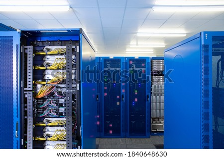 Modern interior of a network server room including racks and cabinets with mesh doors