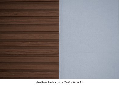 Modern interior wall background split into two textures: dark brown fluted wood paneling and a plain, light gray textured wallpaper