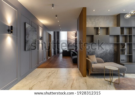 Modern interiro of luxury spacious private house. Grey tones. Wooden design. Cozy sofa. Living room. Shelves and cabinets on wall.