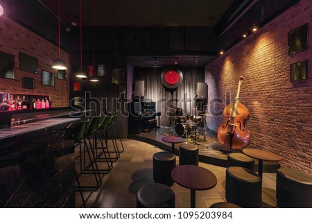 Modern jazz bar interior design, stage with black piano and cello, lamps above bar counter