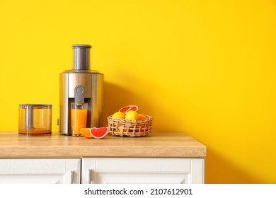 Modern juicer with fresh citrus fruits and glass of juice on table in kitchen