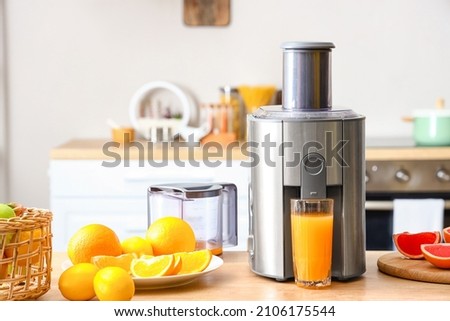 Modern juicer with fresh citrus fruits and glass of juice on table in kitchen Foto d'archivio © 