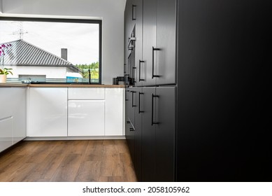 Modern kitchen with black fronts, built in oven and microwave, vinyl panels on the floor. - Shutterstock ID 2058105962