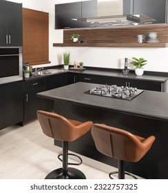 a modern kitchen with black and gray counters and brown chairs in it, close up view - Shutterstock ID 2322757325
