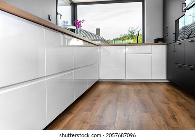 A modern kitchen with built in cabinets against the wall with white fronts, vinyl panels on the floor.