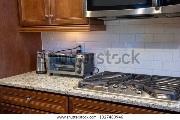 A Modern Kitchen counter of granite with can\
opener, toaster oven and gas\
cooktop
