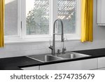 A modern kitchen features a double basin stainless steel sink with a stainless steel faucet, subway tile backsplash, black granite countertop, and yellow curtains.