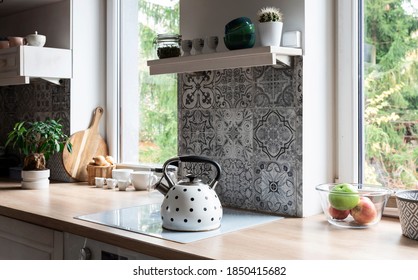 Modern kitchen with grey design tiles and wooden furniture. Big window and plant in scandinavian interior of kitchen. Cozy home in white color. - Shutterstock ID 1850415682