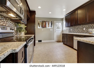 Modern Kitchen Interior With Dark Brown Storage Cabinets With Granite Counter Tops And New Tile Floor