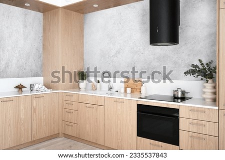 modern kitchen interior, extractor hood, wooden cabinet furniture with white countertop, integrated electric oven and glass ceramic stove, vase and kitchenware