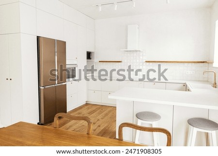 Modern kitchen interior. Stylish white kitchen cabinets with brass knobs, granite island and appliances in new scandinavian house. Modern minimal kitchen design