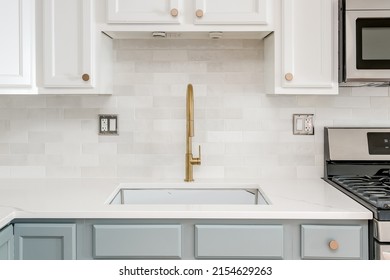 Modern Kitchen Interior. White Kitchen. Contemporary Kitchen Design With White Cabinets, Backsplash And Countertops. Gold Kitchen Faucet And Hardware.