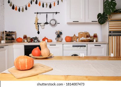 Modern Kitchen In Light Colors With Autumn Decor, Orange Pumpkins For Halloween, Handmade Garland On The Wall, Stylish Furniture And Dishes