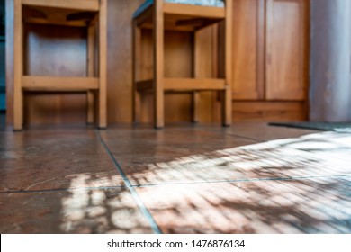 Modern Kitchen Room Tiled Floor Low Angle Closeup With Island And Wooden Bar Stools At Counter In House Or Apartment With Sunlight From Window