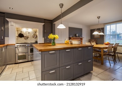 Modern kitchen with traditional looking built in cabinets in grey and white with built in range style oven and breakfast area with table and chairs - Shutterstock ID 2128132919