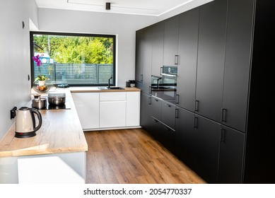 A Modern Kitchen With White And Black Fronts And A Large Corner Window, Vinyl Panels On The Floor.