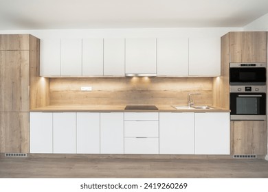 A Modern kitchen with white cabinets, wooden accents, a built-in oven, under-cabinet lighting, and a minimalist countertop. - Powered by Shutterstock