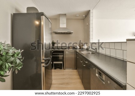 a modern kitchen with wood flooring and stainless appliances on the wall behind it is a black refrigerator freezer