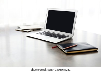Modern laptop with blank screen, modern laptop with notebook and booklet against plain background, office setting - Image