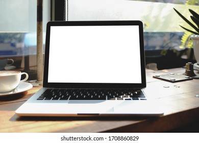 Modern laptop with empty screen on on table and cafe background within coffee shop.