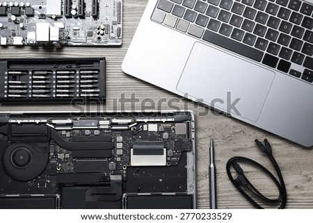 Modern laptop, internal electrical components, screwdriver and set of bits on wooden table, flat lay