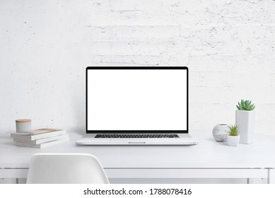 Moderner Laptop mit isoliertem Bildschirm für die Aufnahme auf dem Schreibtisch. Pflanzen und Bücher daneben. Saubere weiße Wand auf Promo-Text