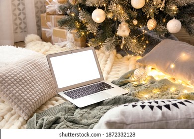 Modern laptop on plaid near Christmas tree - Powered by Shutterstock