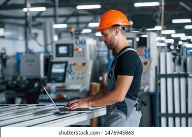 Modern Laptop. Typing On Keyboard. Industrial Worker Indoors In Factory. Young Technician With Orange Hard Hat.