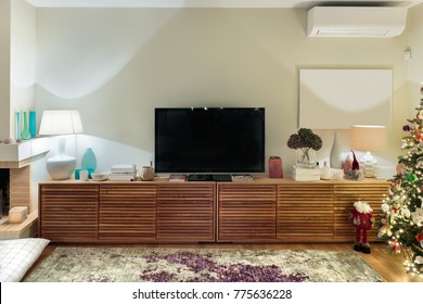 A Modern Large Wooden Cabinet With A Flat TV Placed On A Living Room With A Christmas Tree.