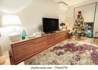 A Modern Large Wooden Cabinet With A Flat TV Placed On A Living Room With A Christmas Tree.