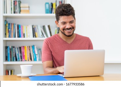 Modern Latin American Man With Beard Working At Computer At Home