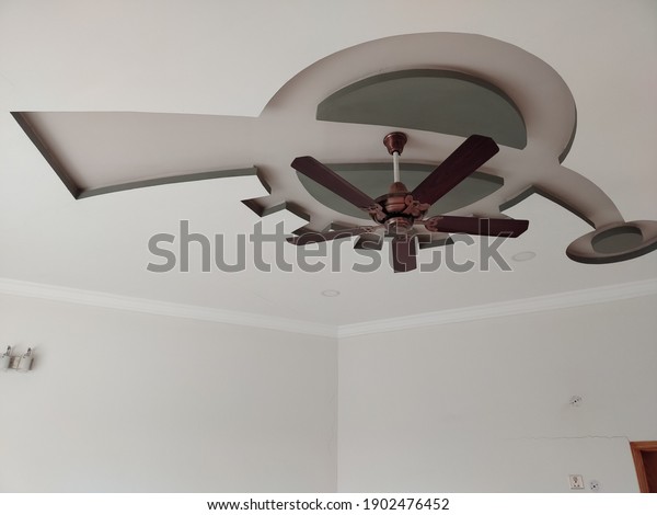 Modern layered ceiling with Stylish Electric ceiling\
fan. Decorative bedroom new Ceiling design with modern electric\
ceiling fan.