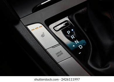 Modern leather interior of the new car. Gear stick with multimedia console. Button for shifting gears on modern car. Seat heating button on the car console.