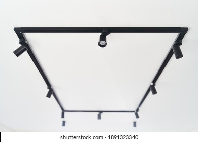 Modern LED black track spot lights in the interior. Hanging lamps spotlights attached to a concrete ceiling in an office loft room