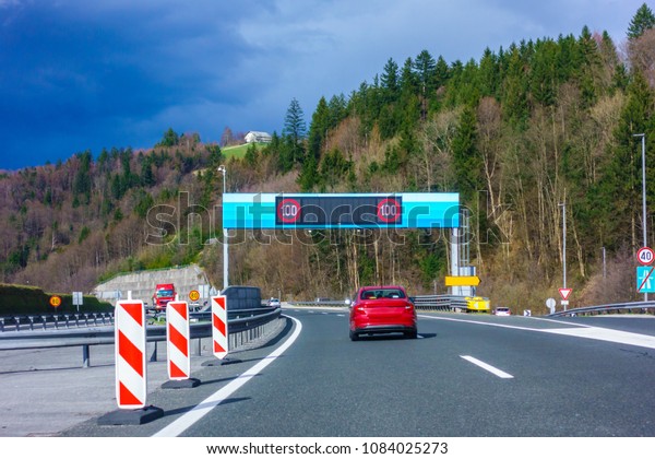 Modern LED traffic signs on Slovenian\
highway A1 near Trojane, red car, truck on\
road