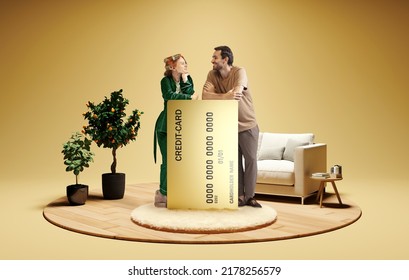 Modern Lifestyle. Happy Family Couple Standing Near To Huge 3d Model Of Credit Card At Home Interior Isolated On Golden Color Background. New App, Mortgage, Lending, Ad Concept