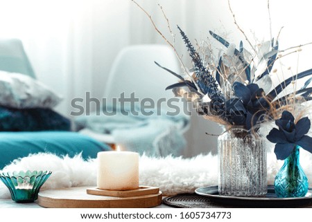 Modern living room, with artificial flowers in a vase and home decor items on a wooden light table.