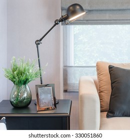 Modern Living Room With Black Lamp On Table Side And Glass Vase Of Plant